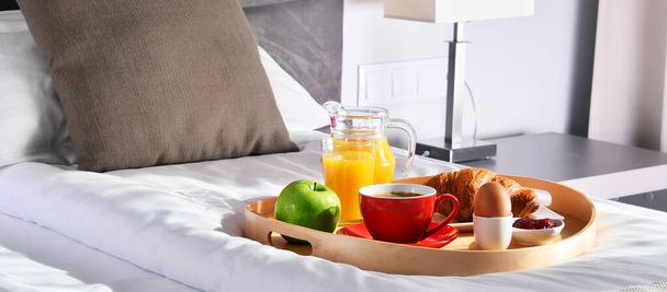 Сніданок на підносі в ліжку в готельному номері
.  - Фото, зображення