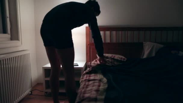 Man prepared to go to sleep. Young man lies down in bed and turns off night stand lamp - Footage, Video