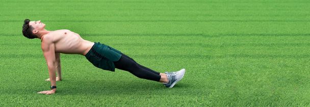 sport man on green grass, copy space. sport reverse plank exercise outdoor. man training reverse plank sport exercise. sport and fitness. - Foto, Imagem