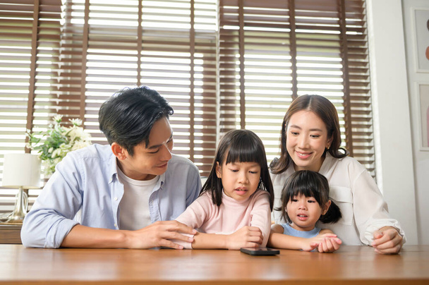Asian family with children holding smartphone and making video call at home - Foto, immagini