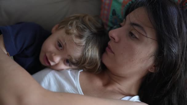 Μητέρα και παιδί αγκαλιάζονται ξαπλωμένοι στον καναπέ στο σπίτι. Μητέρα τρυφερή αγάπη και στοργή με μικρό παιδί. - Πλάνα, βίντεο