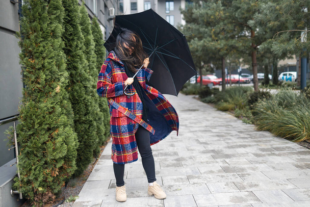 Güçlü rüzgarda şemsiyesini tutmaya çalışan bir kadın. - Fotoğraf, Görsel
