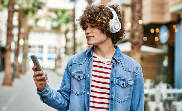 Young hispanic man listening to music from smartphone at the city - Foto, imagen