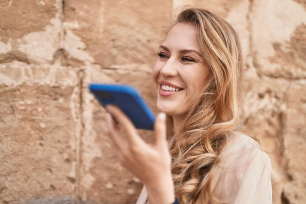 Молода блондинка посміхається впевнено розмовляє на смартфоні в парку
 - Фото, зображення