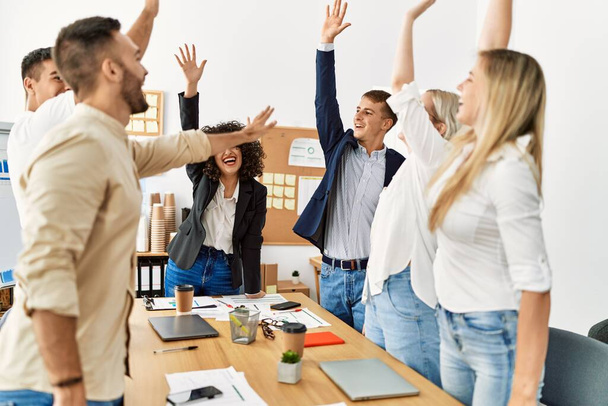 Gruppe von Geschäftsleuten lächelt glücklich und feiert mit erhobenen Händen im Büro. - Foto, Bild