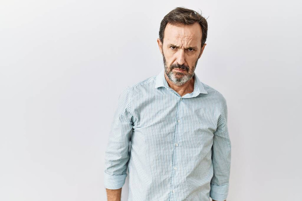 Middle age hispanic man with beard standing over isolated background skeptic and nervous, frowning upset because of problem. negative person.  - Photo, Image