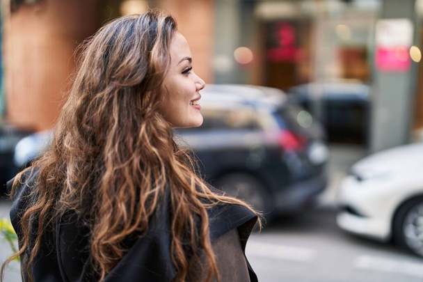 Young beautiful hispanic woman smiling confident looking to the side at street - Фото, изображение