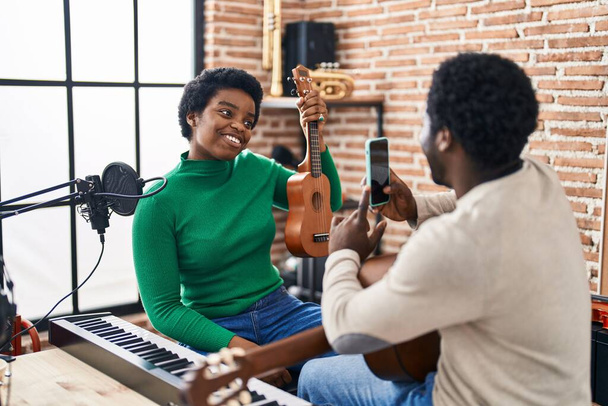 Africano americano hombre y mujer grupo de música hacer foto celebración ukelele en estudio de música - Foto, imagen