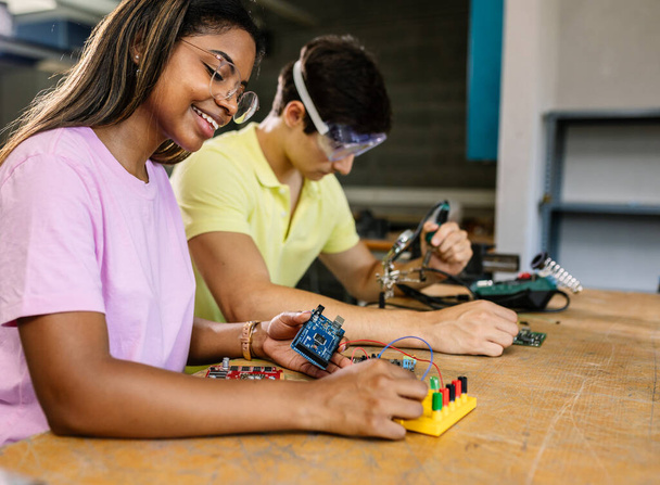 若い多様な学生は、茎ロボット教室で一緒に学ぶ-ヒスパニックラテン女性は学校で電子回路を構築します - 写真・画像