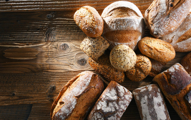 Склад з різноманітними хлібобулочними виробами на дерев'яному столі
. - Фото, зображення