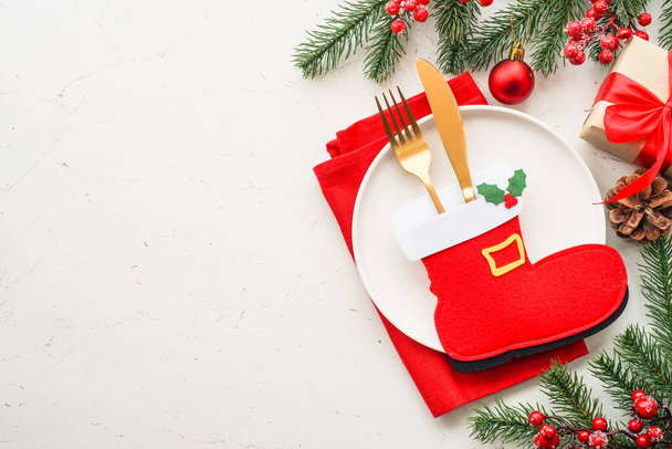 Kersttafel gedekt. Wit bord, bestek, rode en gouden versieringen. Bovenaanzicht aan witte tafel. - Foto, afbeelding