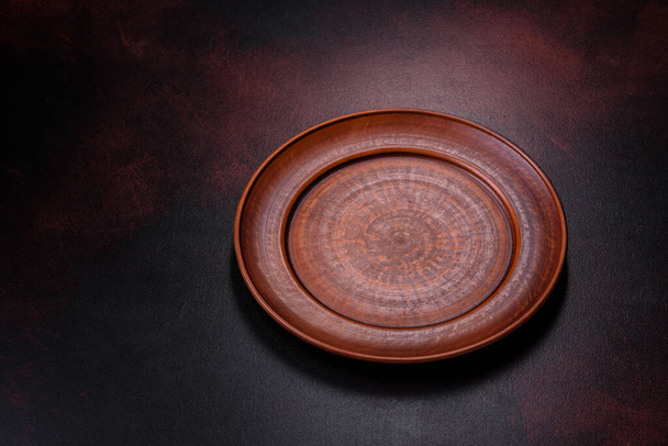 An empty brown ceramic plate on a dark concrete brown background. Preparing the Dinner Table - Photo, Image