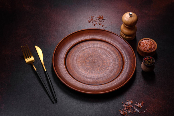 Пустая коричневая керамическая плита на темно-бетонном коричневом фоне. Подготовка обеденного стола - Фото, изображение