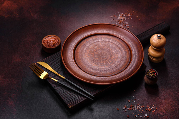 Un piatto di ceramica marrone vuoto su fondo marrone scuro. Preparare la Tavola della Cena - Foto, immagini