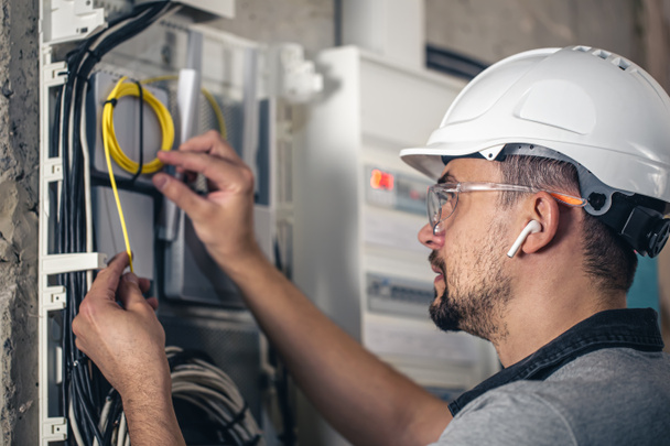 Man, an electrical technician working in a switchboard with fuses. Installation and connection of electrical equipment. - Photo, Image