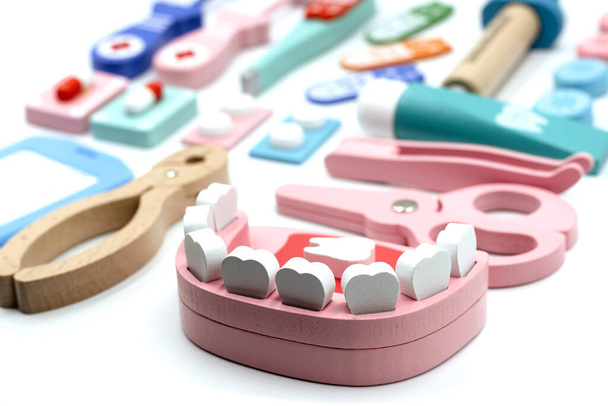 Зуб, зубная паста, зубная щетка, зубное зеркало на розовом фоне. Концепция ежедневной стоматологической помощи и профилактики кариеса. Детская игрушка Деревянный стоматологический набор - Фото, изображение