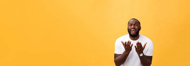 Студийный портрет молодого афроамериканца в белой рубашке, держащегося за руки в молитве, смотрящего в камеру с вдумчивым скептическим выражением на лице, подозревающего в чем-то. Язык тела
 - Фото, изображение