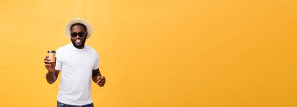 黄色背景に分離を離れてコーヒーのカップを保持しているスタイリッシュな若いアフリカ系アメリカ人 - 写真・画像