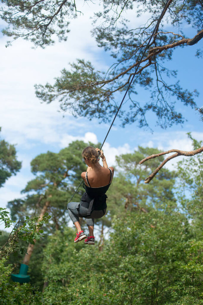 Teenage girl on a zip line in a tree climbing center - Photo, Image