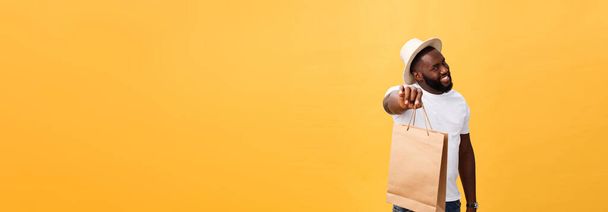 Happy african american man holding shopping bags on yellow background. Holidays concept. - Foto, Imagem