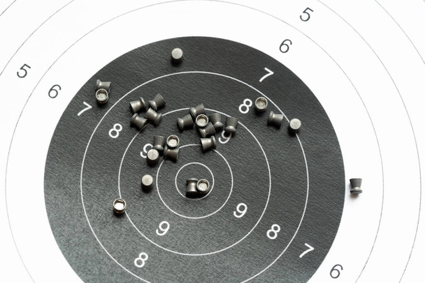 Simple shooting target and lots of metal pellets laying on top of it, object closeup, detail, nobody. Airguns, sport. Pellet ammo, air gun ammunition, range aim training, practice concept, no people - Photo, Image