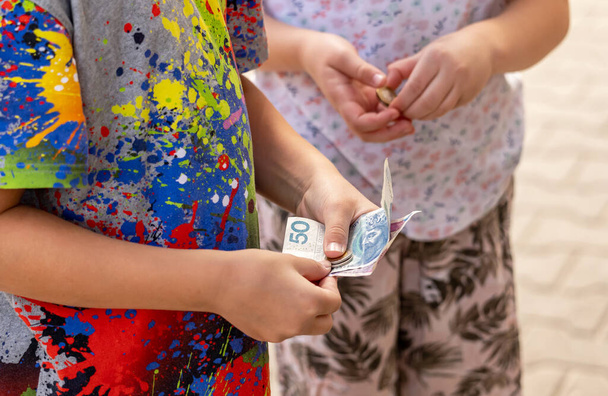 Dvě anonymní děti držící v ruce polské peníze, bankovky, bankovky a mince, detail. Děti dostávající kapesné, měsíční příspěvek jednoduchý koncept, podnikání, správa rodinných financí - Fotografie, Obrázek