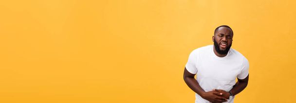 Jeune homme afro-américain portant un t-shirt blanc avec la main sur le ventre parce que les nausées, la maladie douloureuse se sentent mal. Concept Ache
. - Photo, image