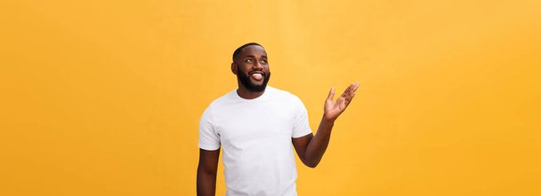 Afrikkalainen amerikkalainen mies parta osoittaa käsi pois puolella eristetty keltaisella pohjalla
. - Valokuva, kuva