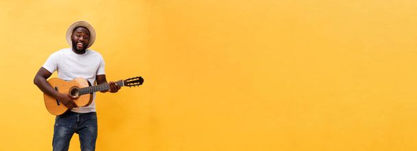 Ολόσωμο φωτογραφία συγκινημένο άνθρωπο καλλιτεχνική παίζοντας την κιθάρα του σε casual σουίτα. Απομονωμένα σε κίτρινο φόντο - Φωτογραφία, εικόνα