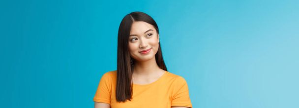 Close-up dromerig hoopvol charmant jong aziatisch vrouw dragen geel t-shirt draaien zijwaarts glimlachen blij, overwegen mooie zomer landschap buiten raam zitten kantoor zorgeloos, blauwe achtergrond. - Foto, afbeelding