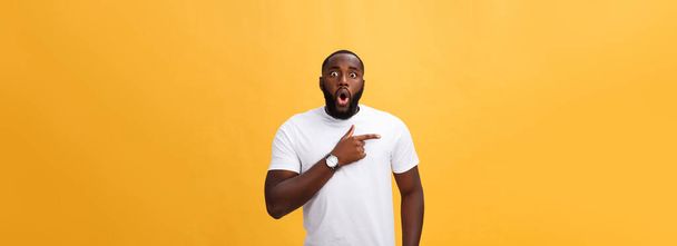 Verbaasd jonge African American hipster dragen witte t-shirt bedrijf handen in verrast gebaar, houden van mond wijd open, op zoek geschokt. - Foto, afbeelding