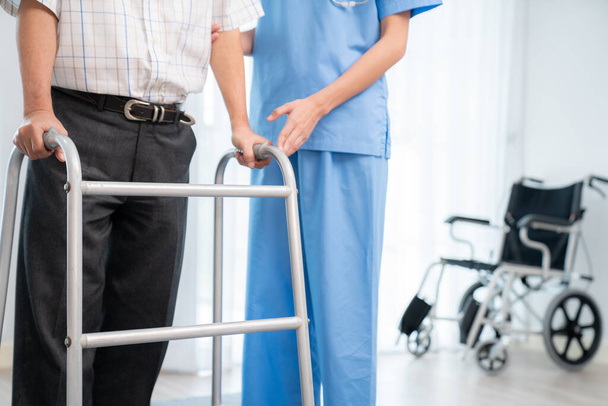 Physiotherapist assists contented senior man on folding walker. Recuperation for elderly, seniors care, nursing home. - Foto, Imagen