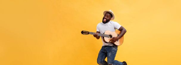 Full-length photo of excited artistic man playing his guitar. Isolated on yellow background - Fotografie, Obrázek