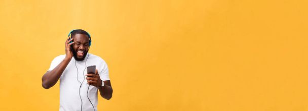 Молодих афро-американських людині носити навушники і насолоджуватися музикою над жовтого золота фону. - Фото, зображення