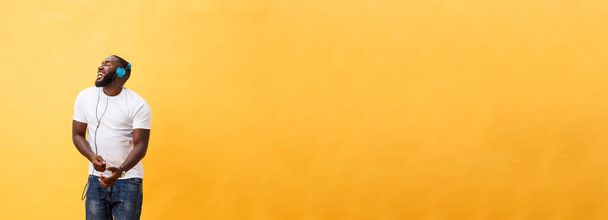 Повна довжина портрет Вишневе афро-американських юнак слухати музику з навушниками і танці ізольовані на жовтому фоні. - Фото, зображення