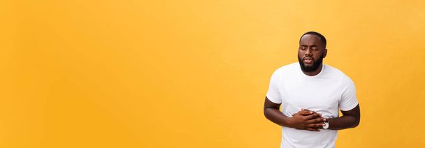 Afro-amerikai fiatalember visel fehér póló, kezével a gyomor, mert hányinger, fájdalmas betegség, rossz közérzet. Ache koncepció. - Fotó, kép