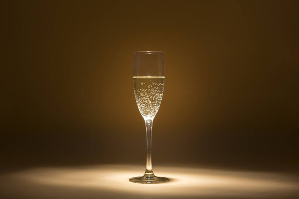 view of a glass of cava in the foreground lit up around it twilight - 写真・画像