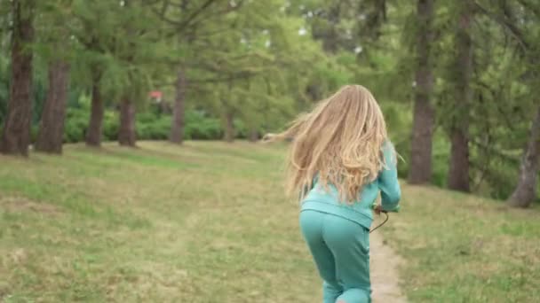 Dospívající dívka jezdí na skútru v parku. Venkovní rekreační životní styl videa. Aktivní životní styl a veselost. Vysoce kvalitní 4K záběry - Záběry, video
