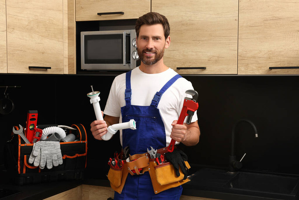 Professional plumber with corrugated pipe and wrench in kitchen - Foto, imagen