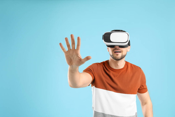 Man using virtual reality headset on light blue background - Foto, Imagen