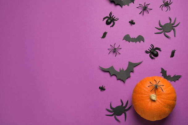 Flat lay composition with pumpkin, spiders and paper bats on purple background, space for text. Halloween celebration - Foto, Bild
