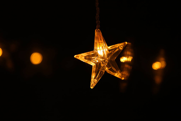 Christmas.Star burning on a black background.Festive glowing garlands on a dark background.Christmas and New Year festive background. - Φωτογραφία, εικόνα