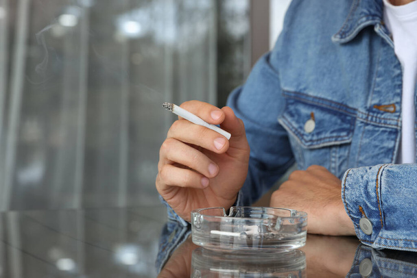 Muž kouření cigarety u stolu v venkovní kavárně, detailní záběr - Fotografie, Obrázek