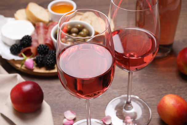 Delicious rose wine and snacks on wooden table, closeup - Foto, imagen