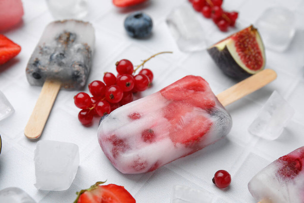 Tasty refreshing berry ice pops on white table, closeup - 写真・画像