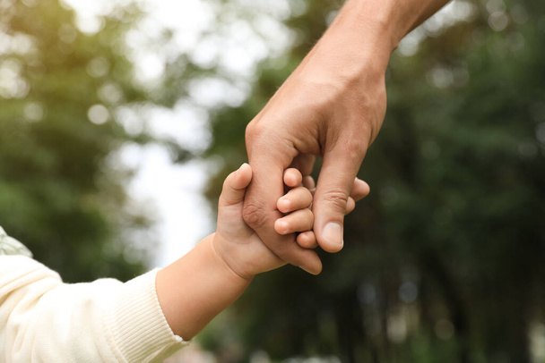 Daughter holding father's hand in park, closeup. Happy family - Fotoğraf, Görsel