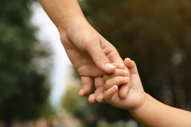 Daughter holding mother's hand in park, closeup. Happy family - Foto, Imagen