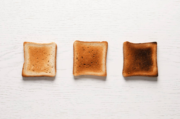 Slices of delicious toasted bread on white wooden table, top view - Фото, зображення