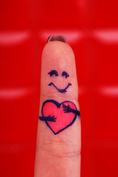 Painted finger on red background - Foto, afbeelding