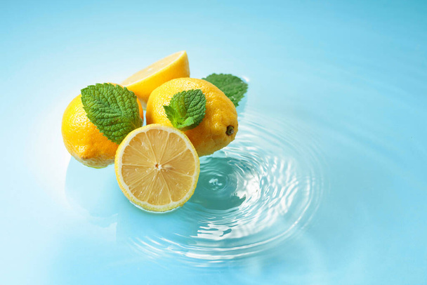 Ripe juicy lemons with mint on a blue background with water splashes. Copy space. - Foto, immagini